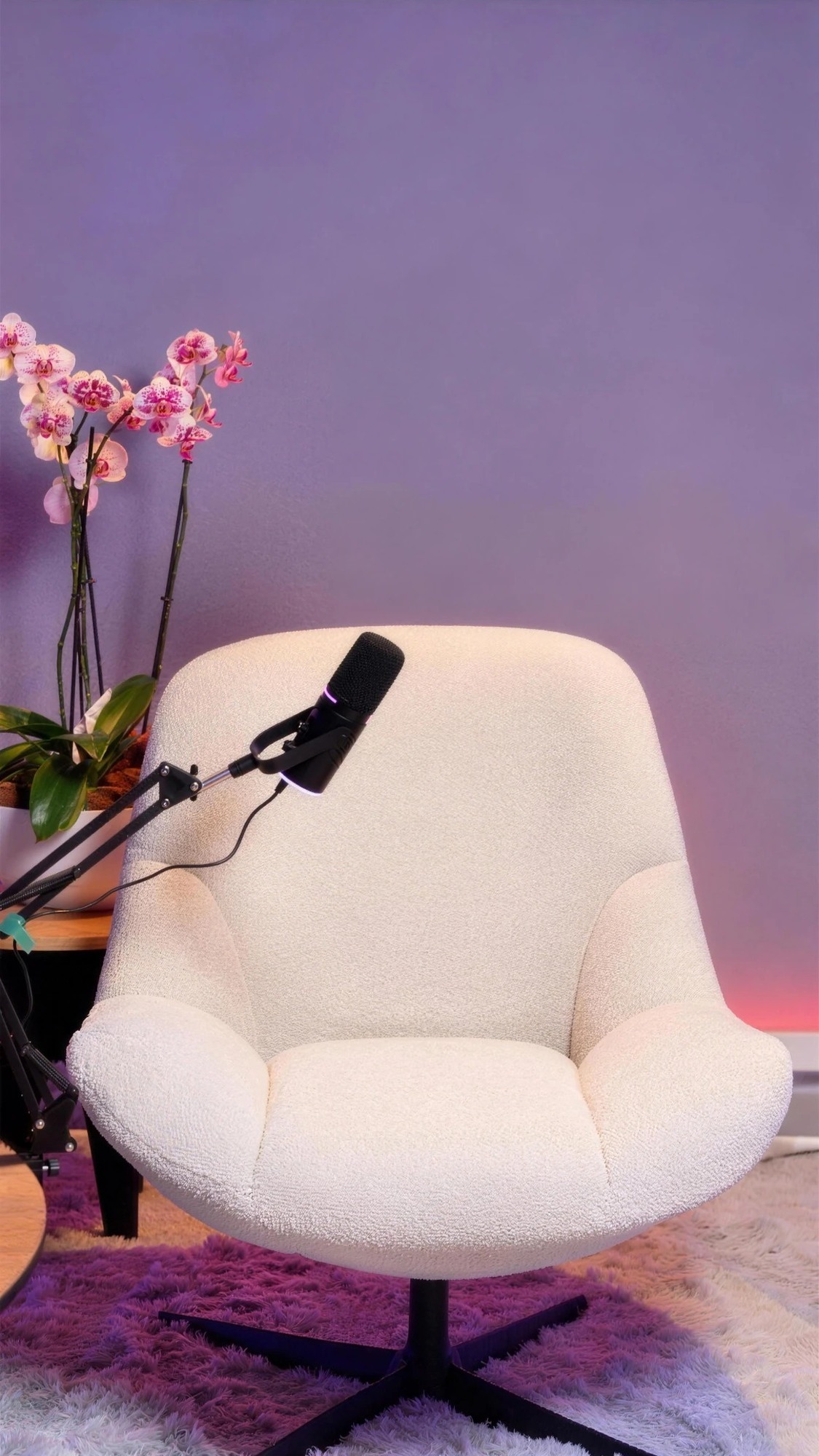Sillón blanco de bouclé con micrófono frente a pared lila y orquídeas
